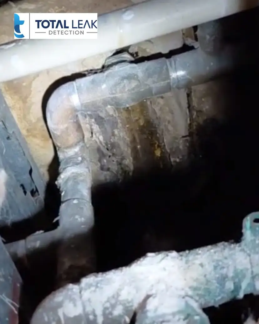 Corroded leaking copper pipes inside a wall cavity.