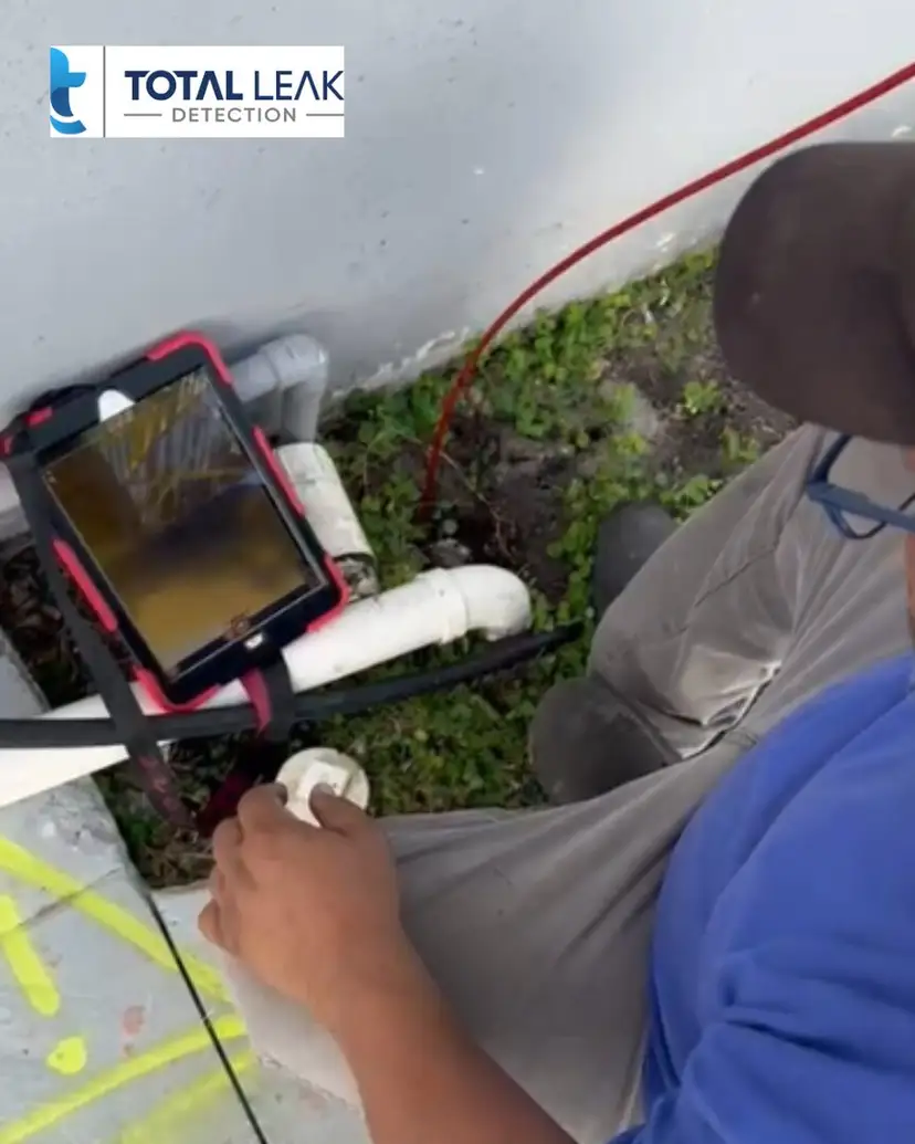 Sewer camera feed on a tablet at an outdoor PVC cleanout.