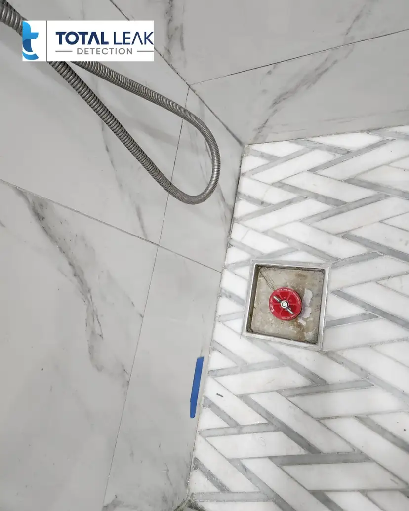 Shower-pan hydrostatic test plug in a marble shower.
